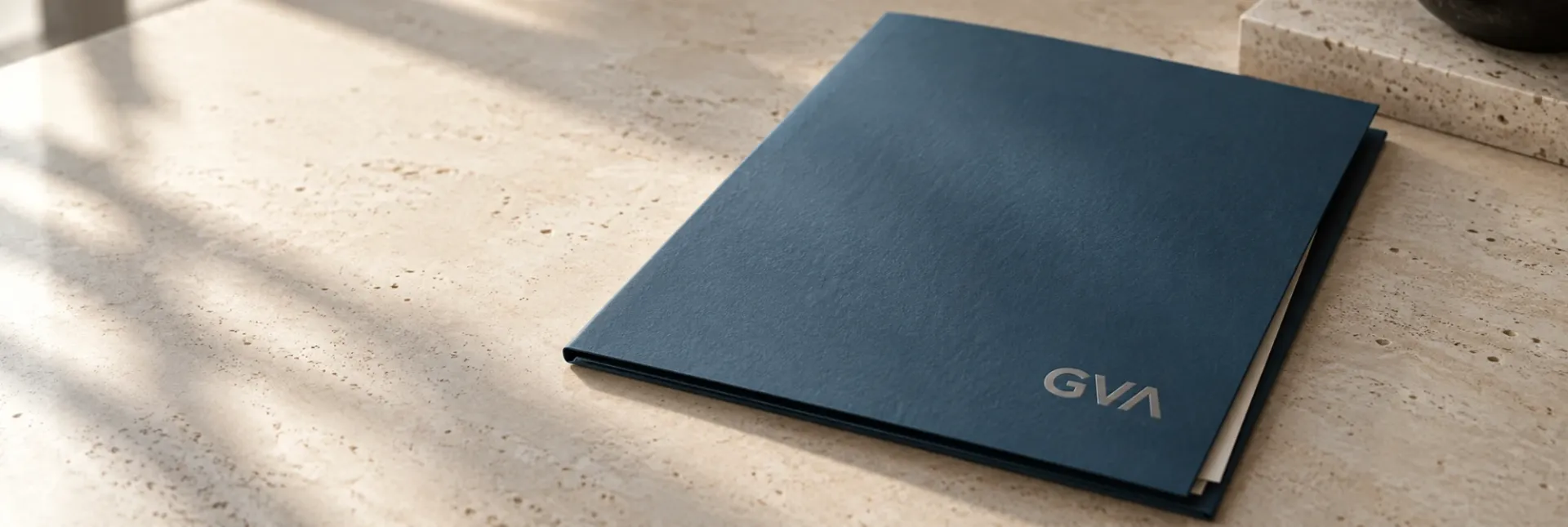 Pasta azul com a marca GVA sobre uma mesa de pedra clara